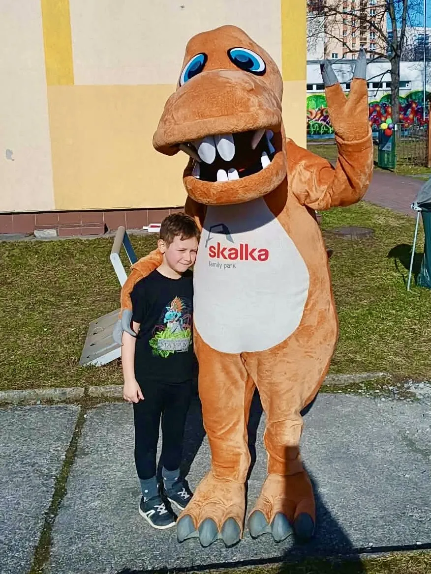 Nekonečný karneval — kluk s maskotem dinosaura