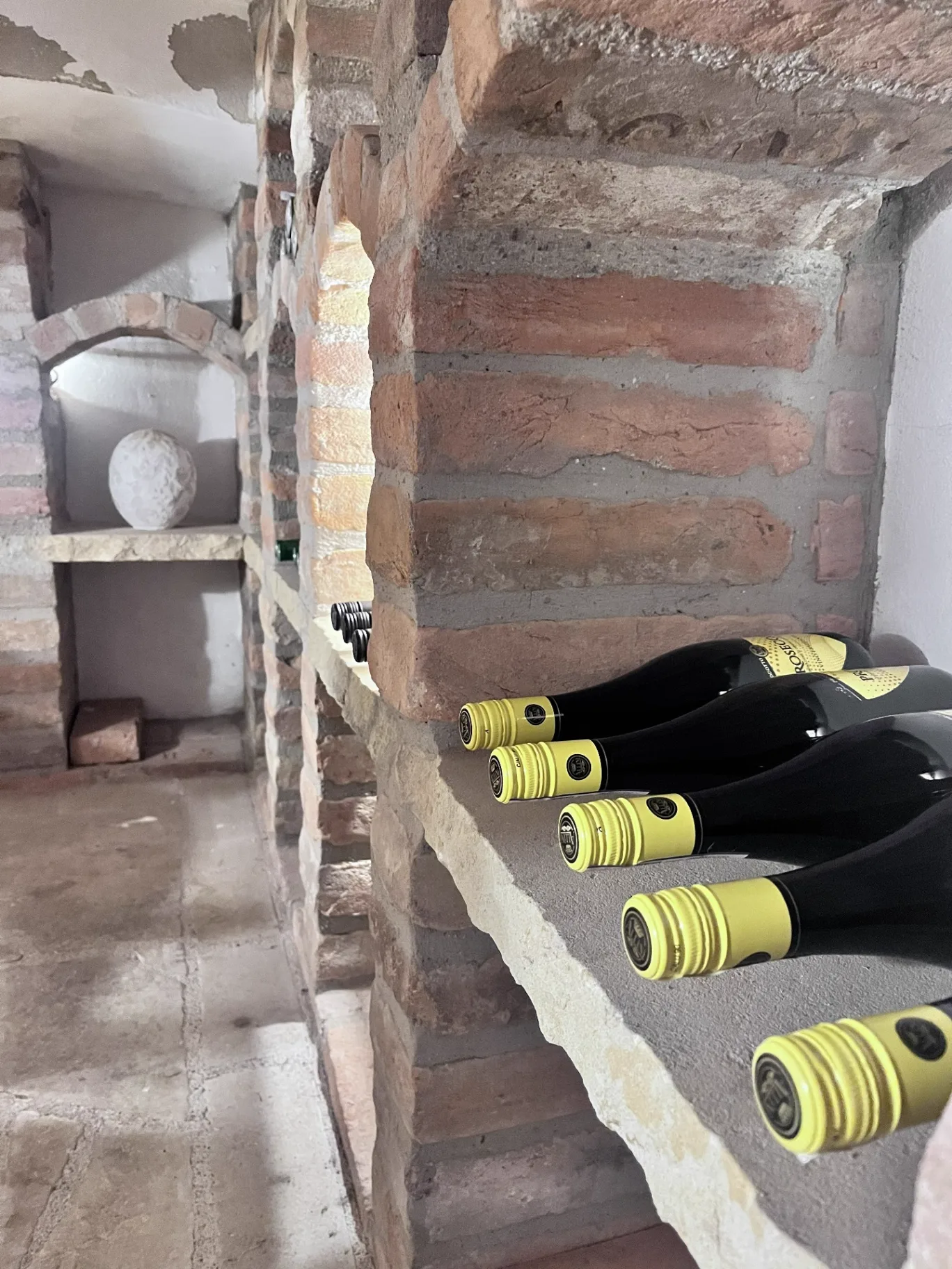 Lahve prosecca v kamenných výklencích sklípku